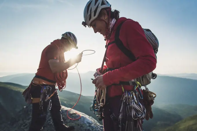 Man & woman sort rock climbing gear during early morning in mountains