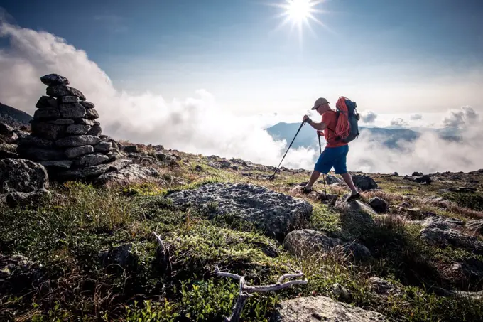 Man hiking through mountains with backpack and hiking poles