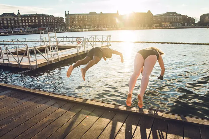 Two Friends of Different Age and Race Jumping in Cold Water in Denmark