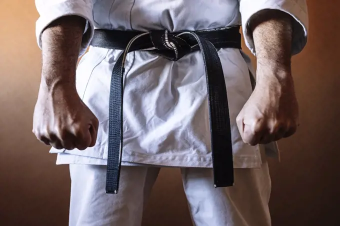 Unrecognizable karateka with black belt in firm position