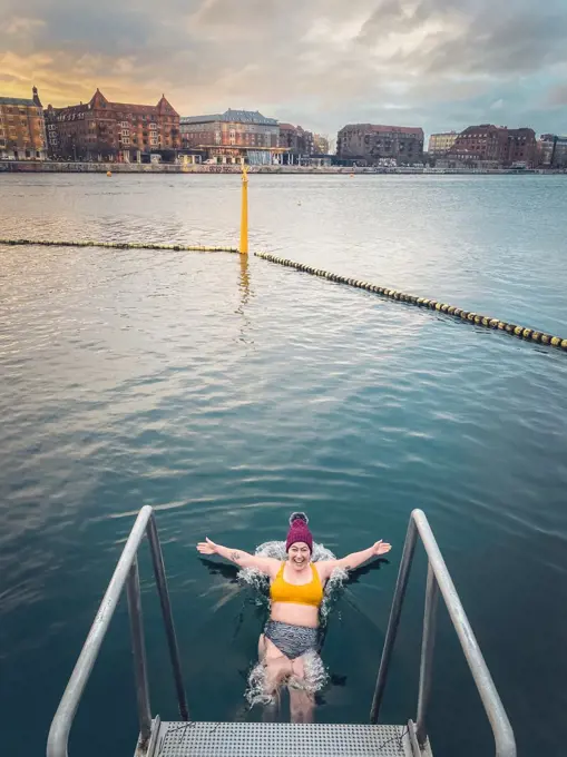 Young Woman At Sunrise Gracefully Falling Into Freezing Water Denmark