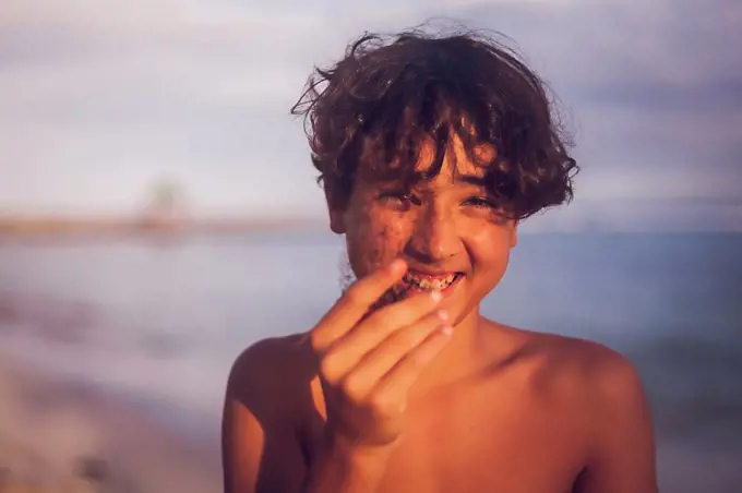 Smiling pre teen boy holding a coral on a tropical beach.