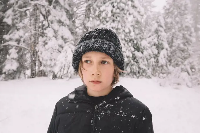 Young Boy in a Beanie Looks Away While Snowflakes Fall around him.