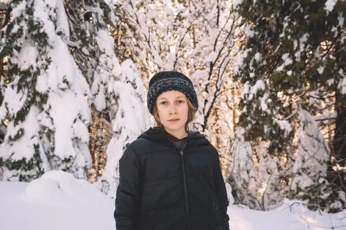 Young Boy in Beanie Stands in a Snowy Scene.