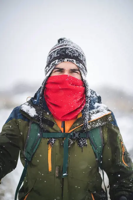 A man with face covered treks under heavy snow