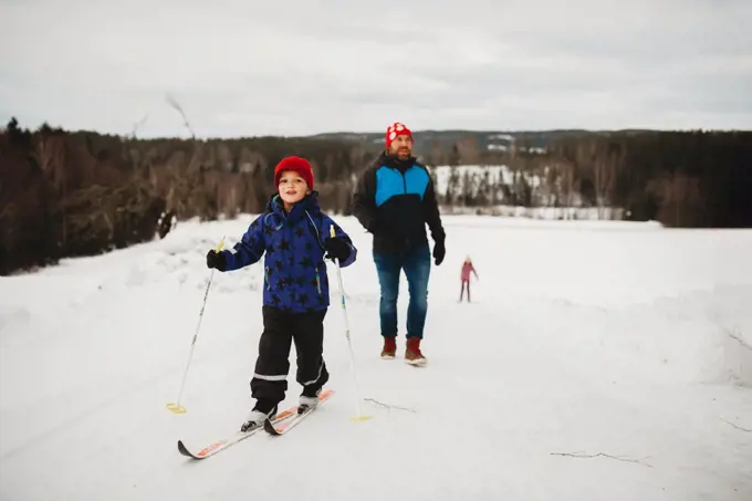 Winter fun boy smiling on skis with family behind him on snowy day