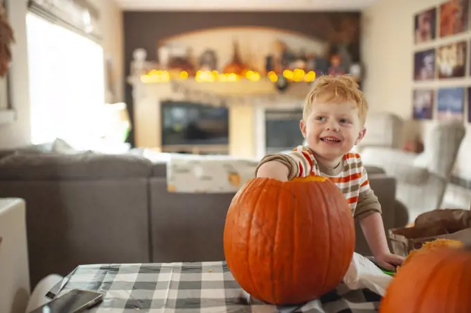 Toddler boy 3-4 years old scoops out pumpkin seeds with his hand