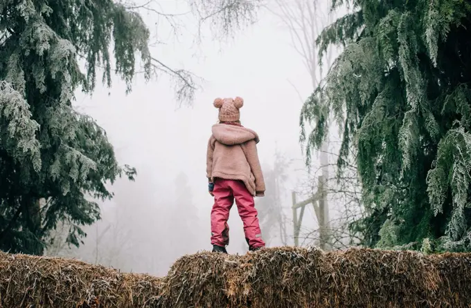 girl stood in the frosty forest looking into the fog in England