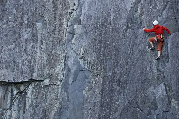 woman climbing up steep rock face at Slate quarry in North Wales