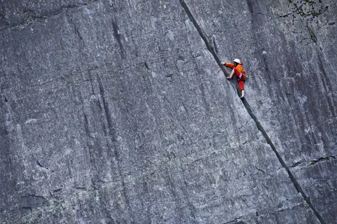 woman climbing up steep rock face at Slate quarry in North Wales