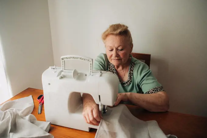 Elder woman working on sewing machine at home