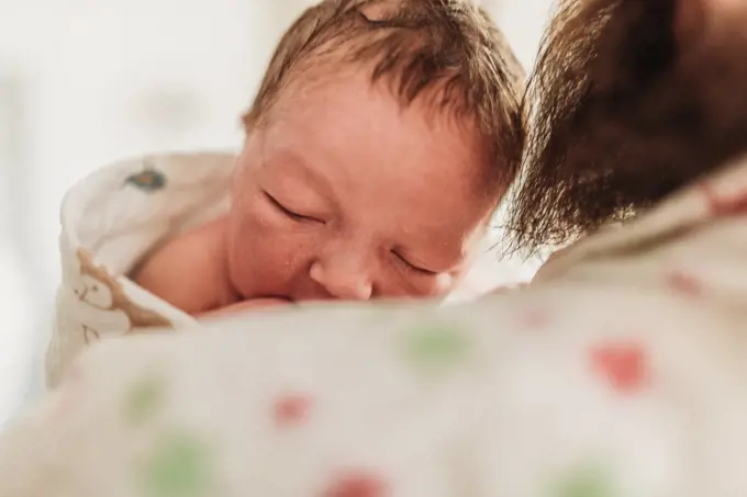 Close up of newborn face resting on new dad