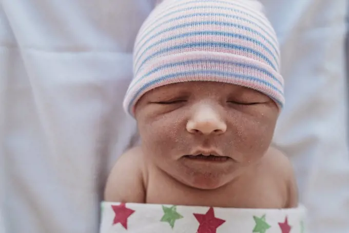 High angled close up view of swaddled newborn in hat at hospital