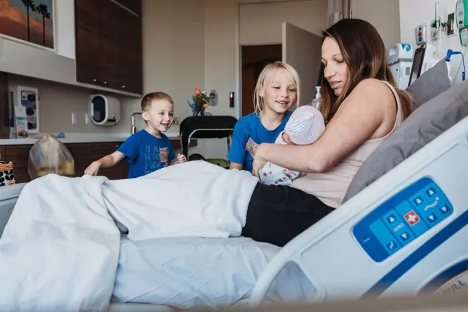 Young brothers meeting newborn baby for the first time in hospital