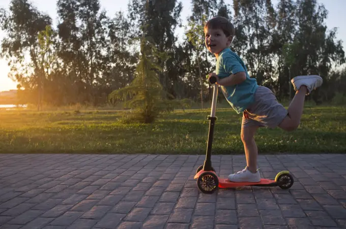 3 years boy riding a scooter a nice sunny spring sunset