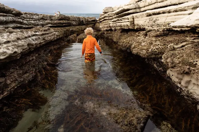 Small child walking in large tide pool in New Zealand