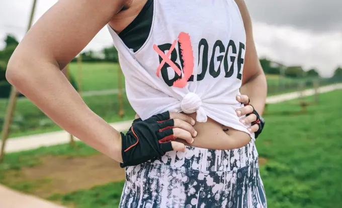 Female athlete with knotted shirt posing