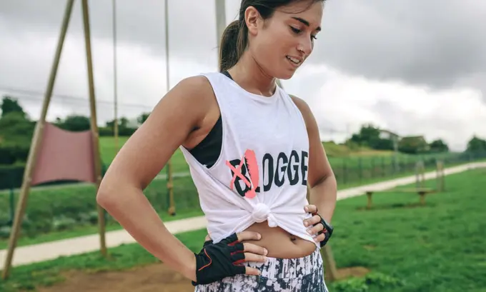 Tired female athlete with knotted shirt