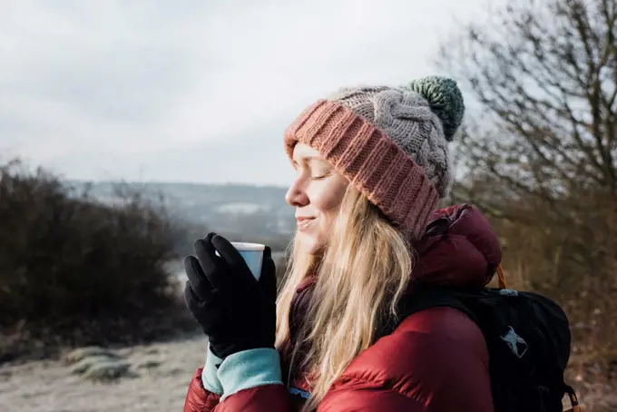 woman smiling holding a hot drink whilst enjoying the cold air in UK