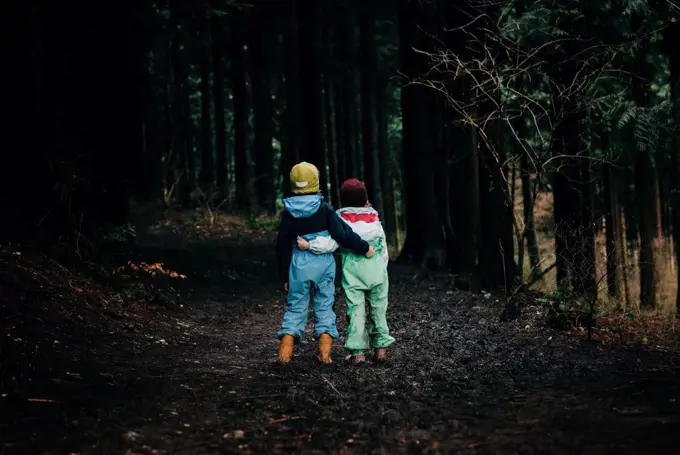 siblings hugging each other walking along the forest talking