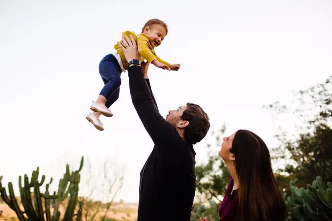 Dad Lifting Smiling Daughter as Mom Watches in San Diego