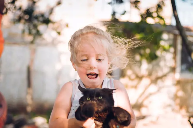 happy little girl playing with kitten