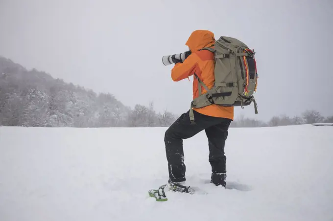 photographer working with snowshoes in covered field