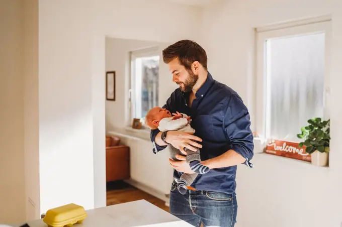 Happy dad holding his newborn baby at home during quarantine