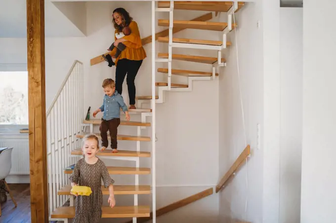 Mom and children walking down the stairs at home during quarantine