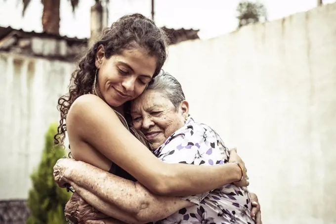 Mexican women smile in loving hug embrace on summer street Mecxico