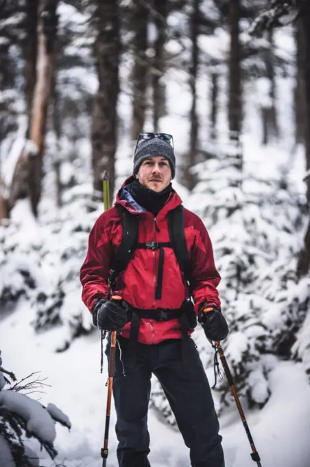 portrait of male skier with red jacket in snow covered woods in Maine