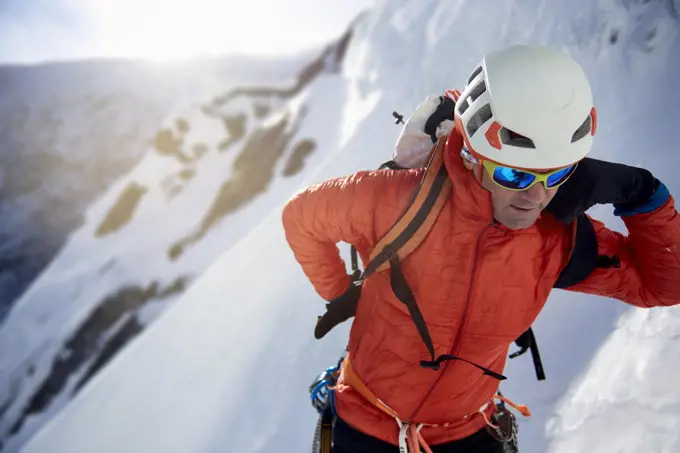 Ice Climber fixing his pack before ice climbing