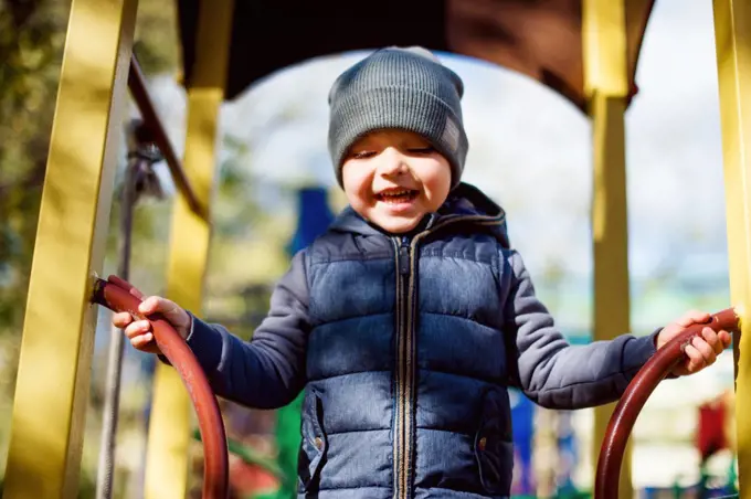 Laughing happy kid at playground, autumn outdoors activity