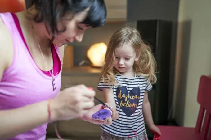 Mother painting on daughter's palms with watercolours