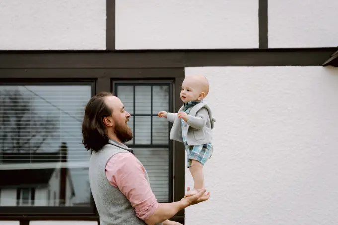 Fun dad playing with baby son in front yard in spring