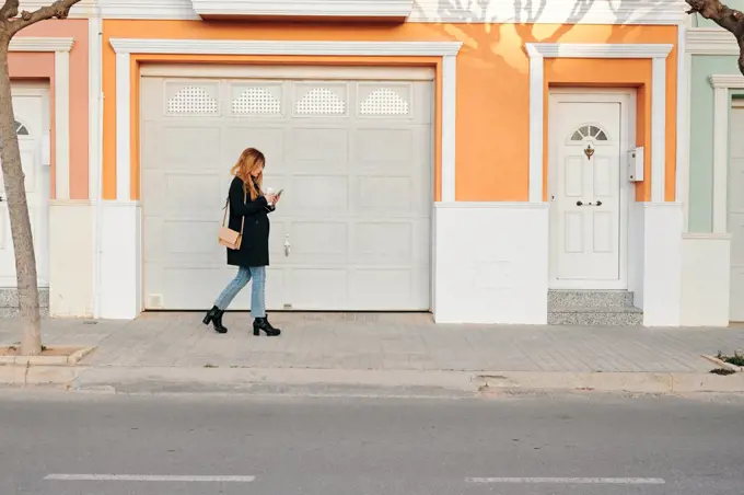 Woman walks while she is looking at her smartphone on the street