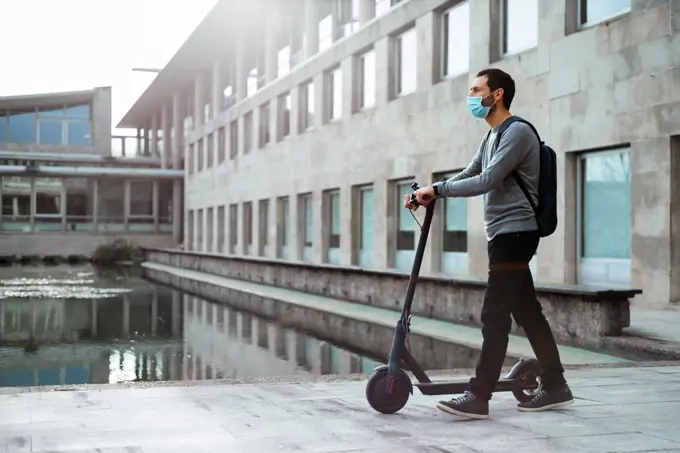 Stylish man walking near electric scooter on street