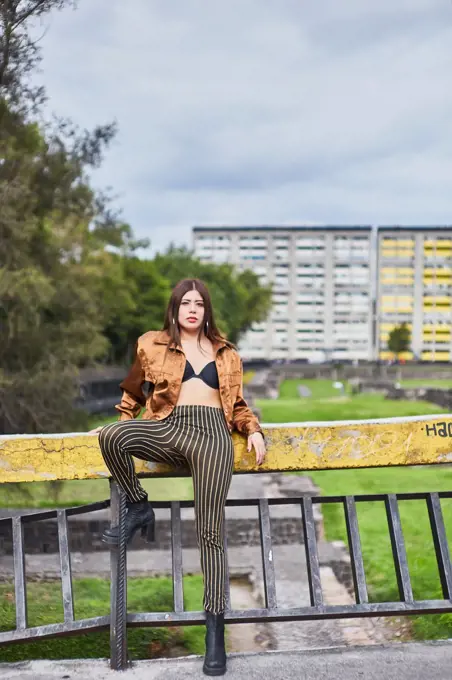 beautiful young woman leaning against a concrete wall in the street