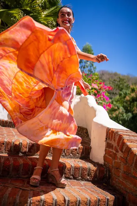 Vertical photo of a woman in a colourful dress flying with the movement