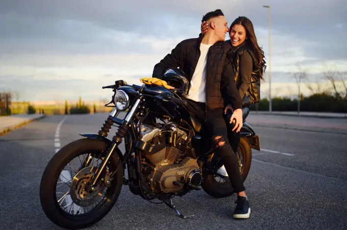 Portrait of happy young couple on scooter enjoying road trip