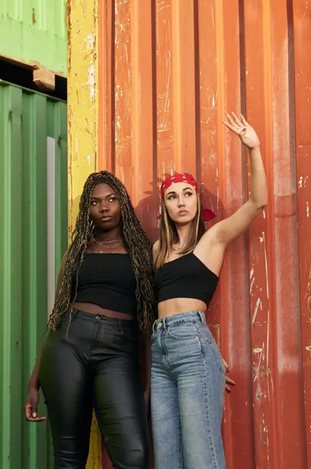 Two multi-ethnic young women in urban clothing pose at sunset