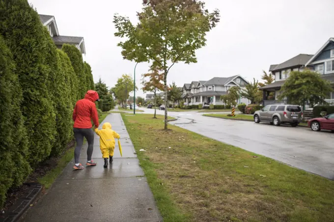 Mother walks with son on sidewalk during a rainy day.