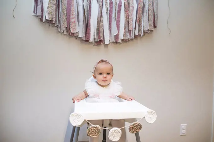 First birthday, baby girl sitting under birthday banner