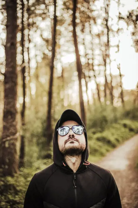 Man with sunglasses and hood in a beautiful forest