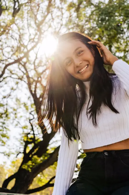 Smiling woman with autumn sunlight from behind.