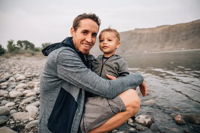 Dad and toddler hugging by yellowstone river on a nature walk
