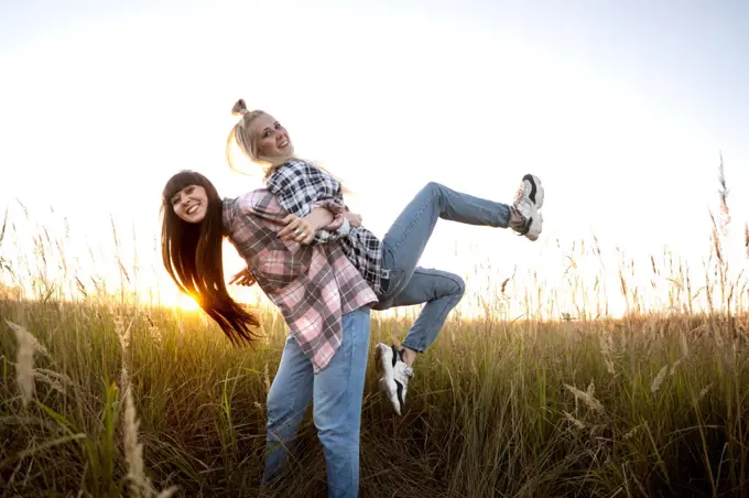 two beautiful twin girls make style in the field at sunset