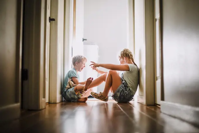 Brother and Sister Playing and Laughing in Bright Hallway