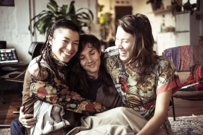 Young alternative female women friends laugh, smile and hug at home