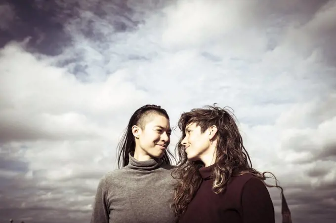 proud queer lesbian couple stand on rooftop with sky above in berlin